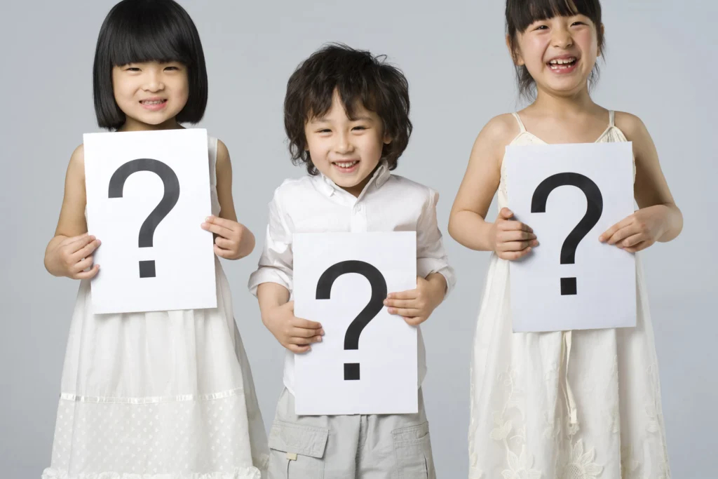 3 different ages children holding a paper with a question mark printed on it